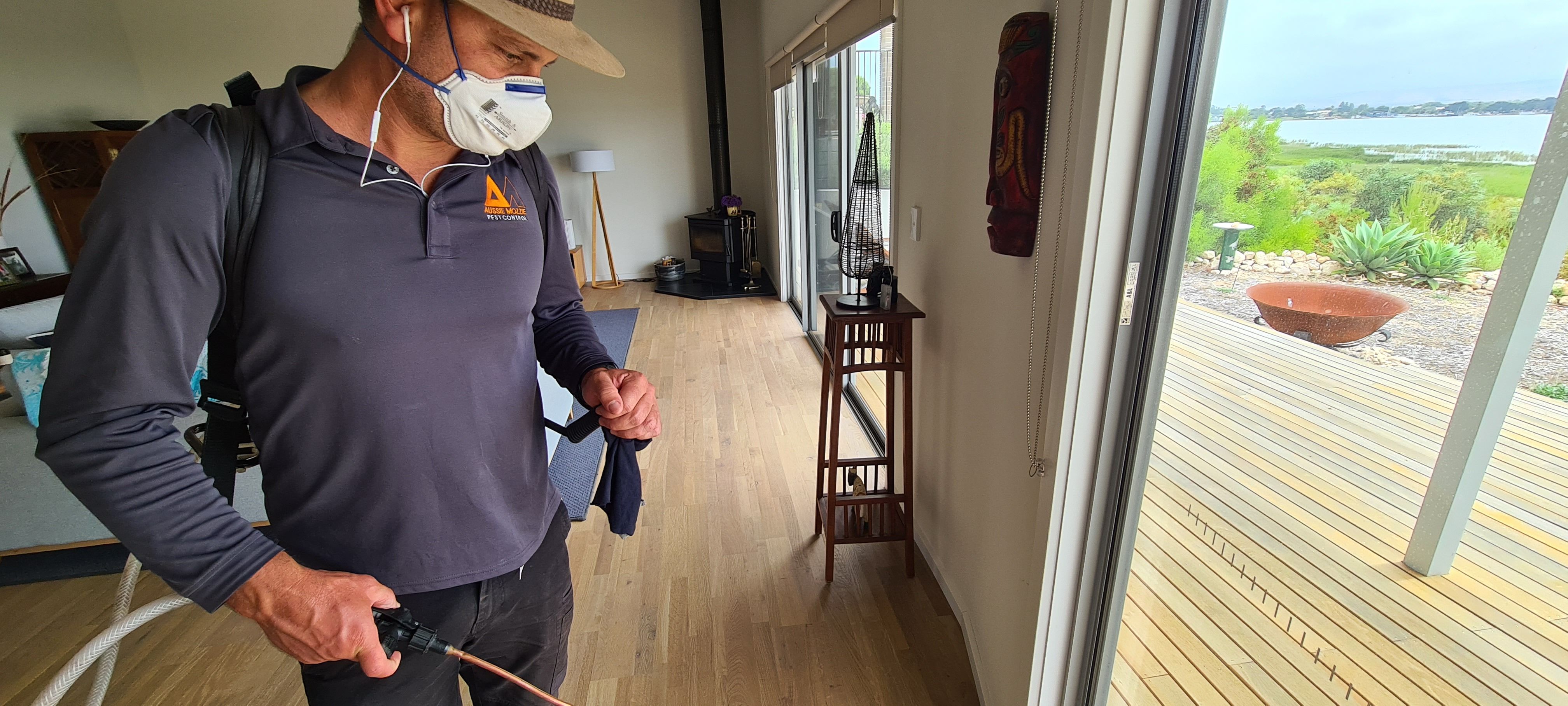 Adam Searl in an Aussie Mozzie shirt and mask, treating a living room
